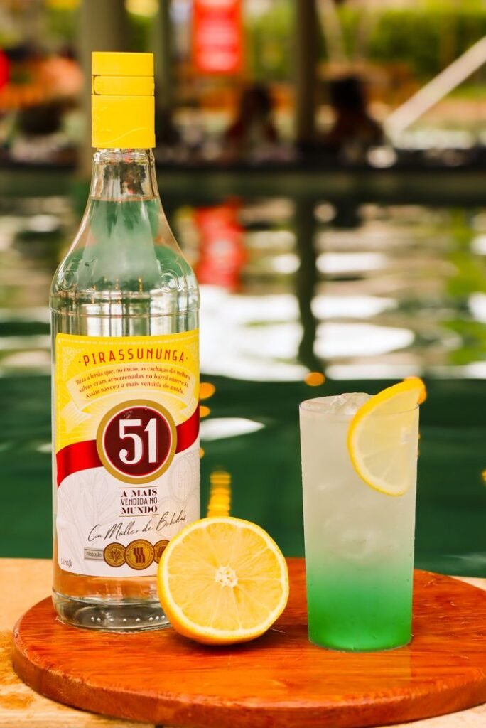 A bright lemon cocktail next to a bottle of Pirassununga by the pool.